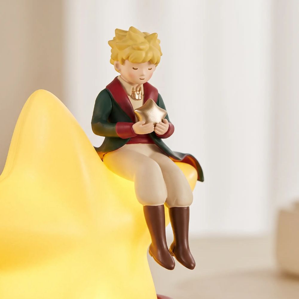 Détail de la figurine du Petit Prince assis sur l'étoile lumineuse de la veilleuse