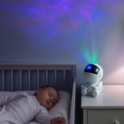 Chambre d’enfant éclairée par une veilleuse projection galaxie